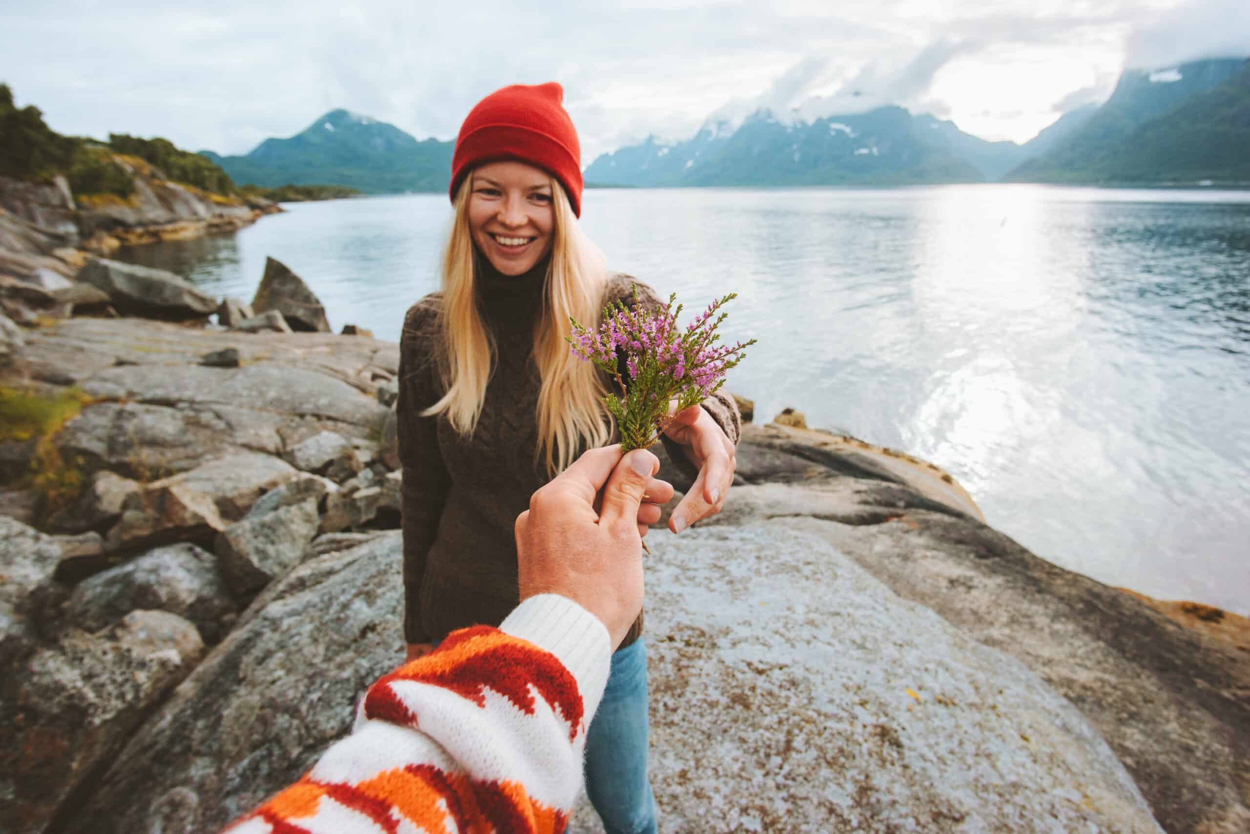 Couple in love man hand giving bouquet flowers to woman travel lifestyle romantic vacations in Norway.