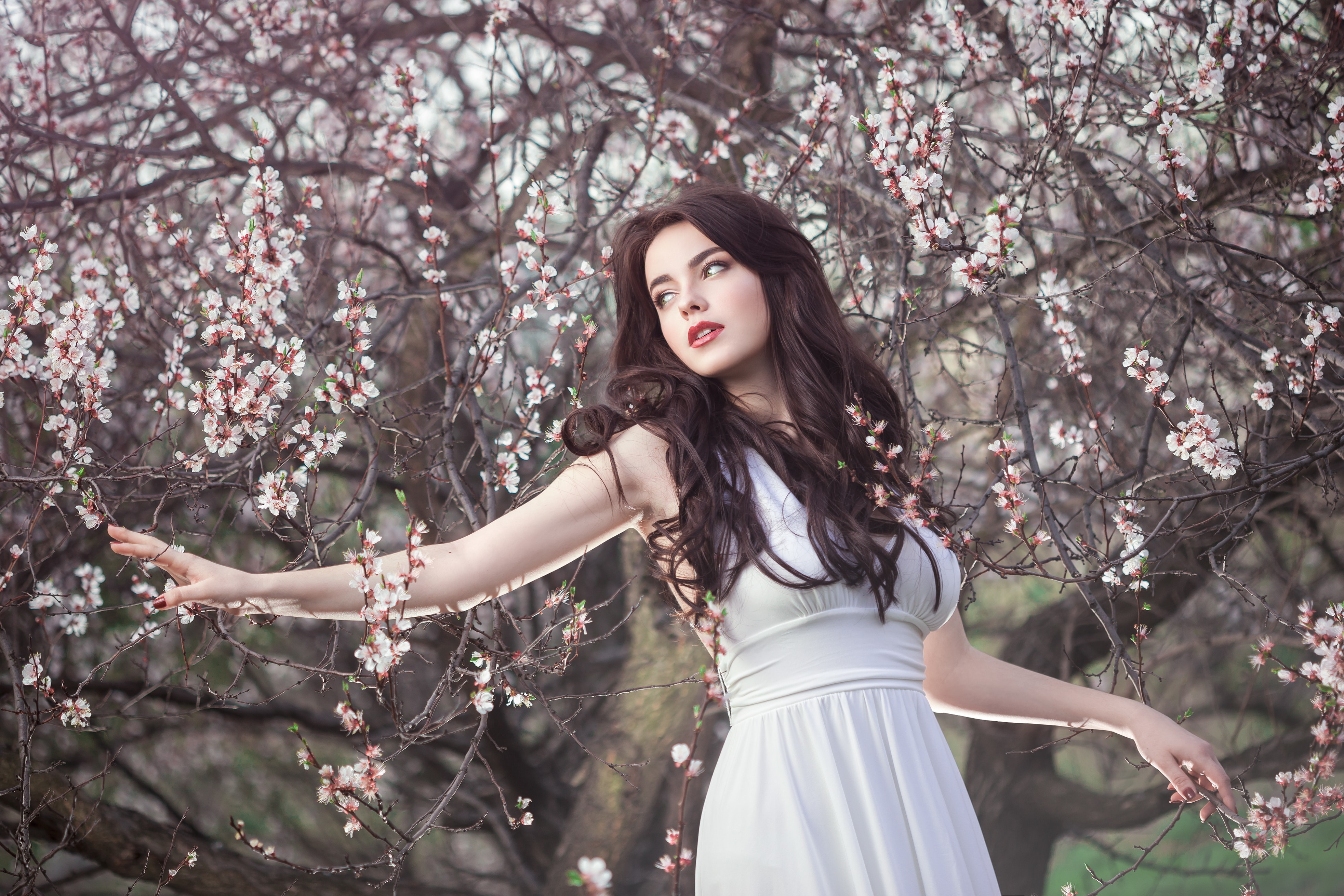 Beautiful girl standing at blossoming tree in the garden