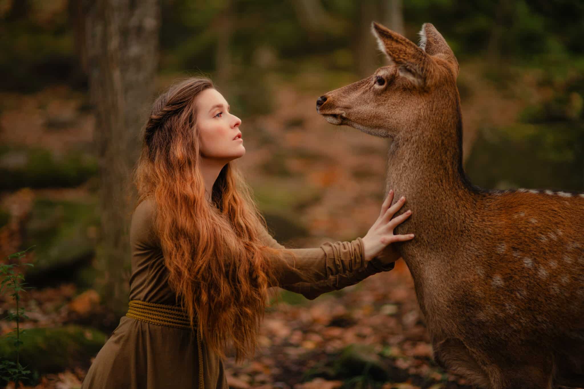 Redhead girl with deer in a long dress.
