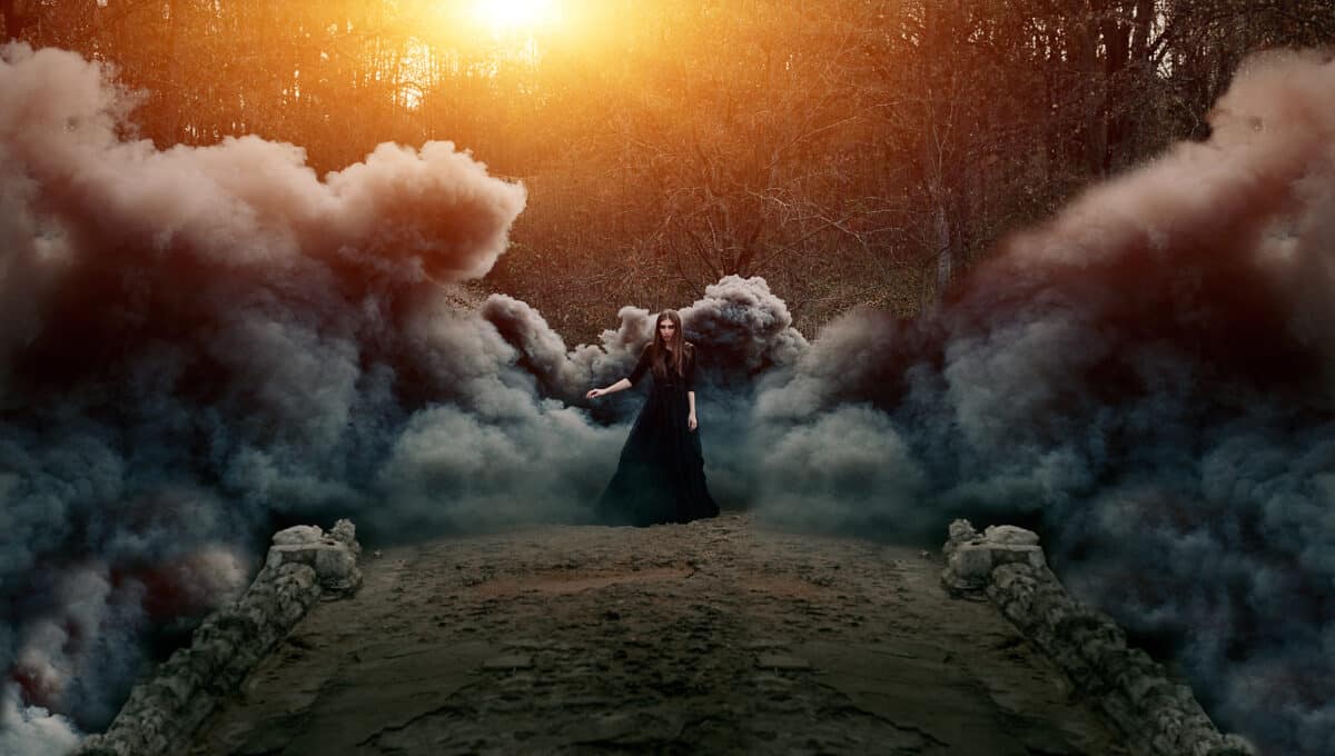 an attractive woman in black walking on the bridge in heavy black smoke and bright light in the background