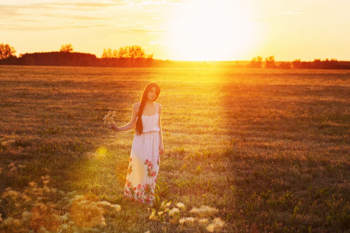 beautiful woman with wild flowers at sunset