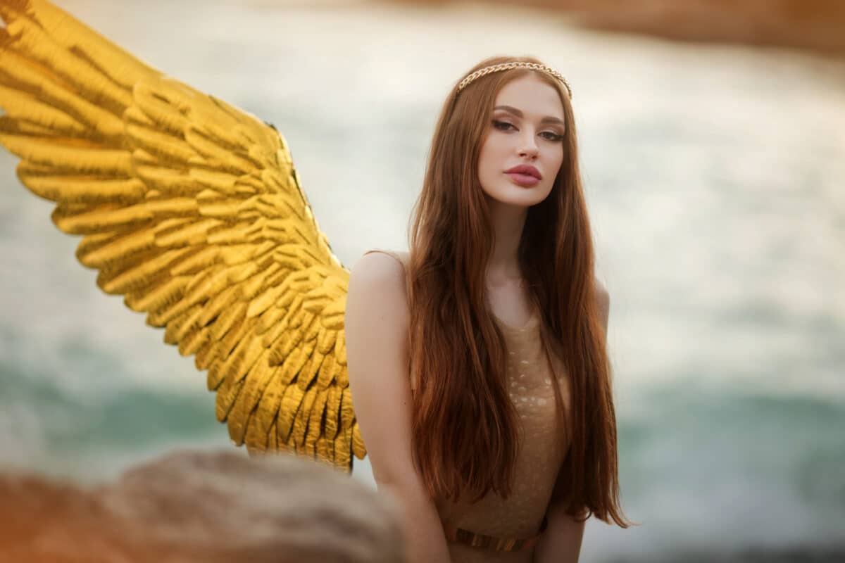 Young beautiful woman with golden bird wings