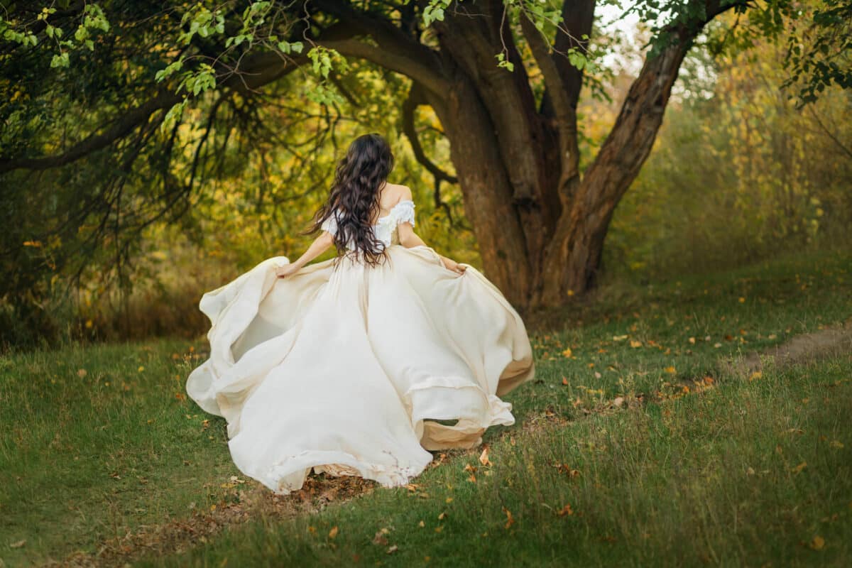 image art portrait fantasy woman in white vintage style dress. queen runs in summer forest. Girl princess long dark hair fly fluttering in wind motion. romantic lady back rear view. Green tree nature