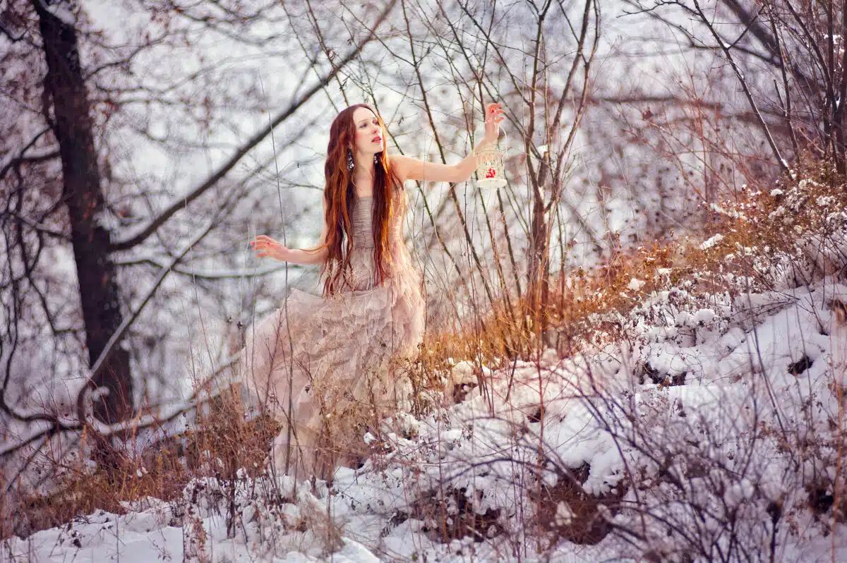 Young beautiful red haired woman walking in the winter forest
