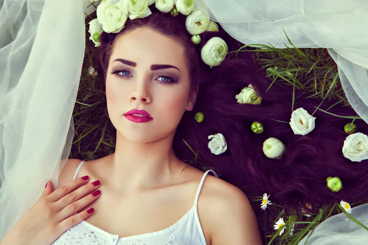 Bride with flowers in hair and veil lying on grass