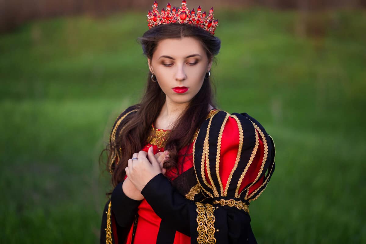 beautiful, young girl in black and red medieval dress with crown on head.