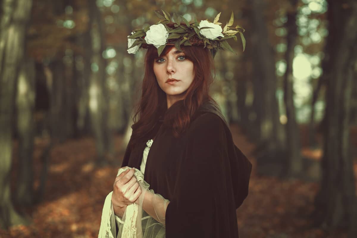 medieval maiden with a head wreath standing in autumn forest