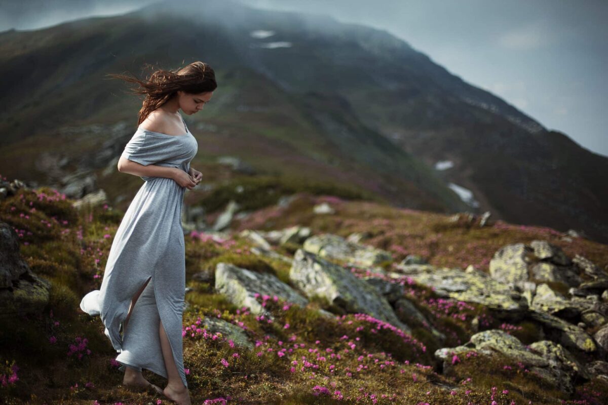 enchanting brunette woman on a mountain with pink flowers