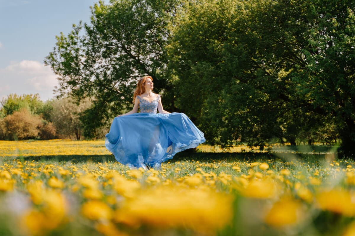 In summer, a cheerful lady runs across a dandelion field