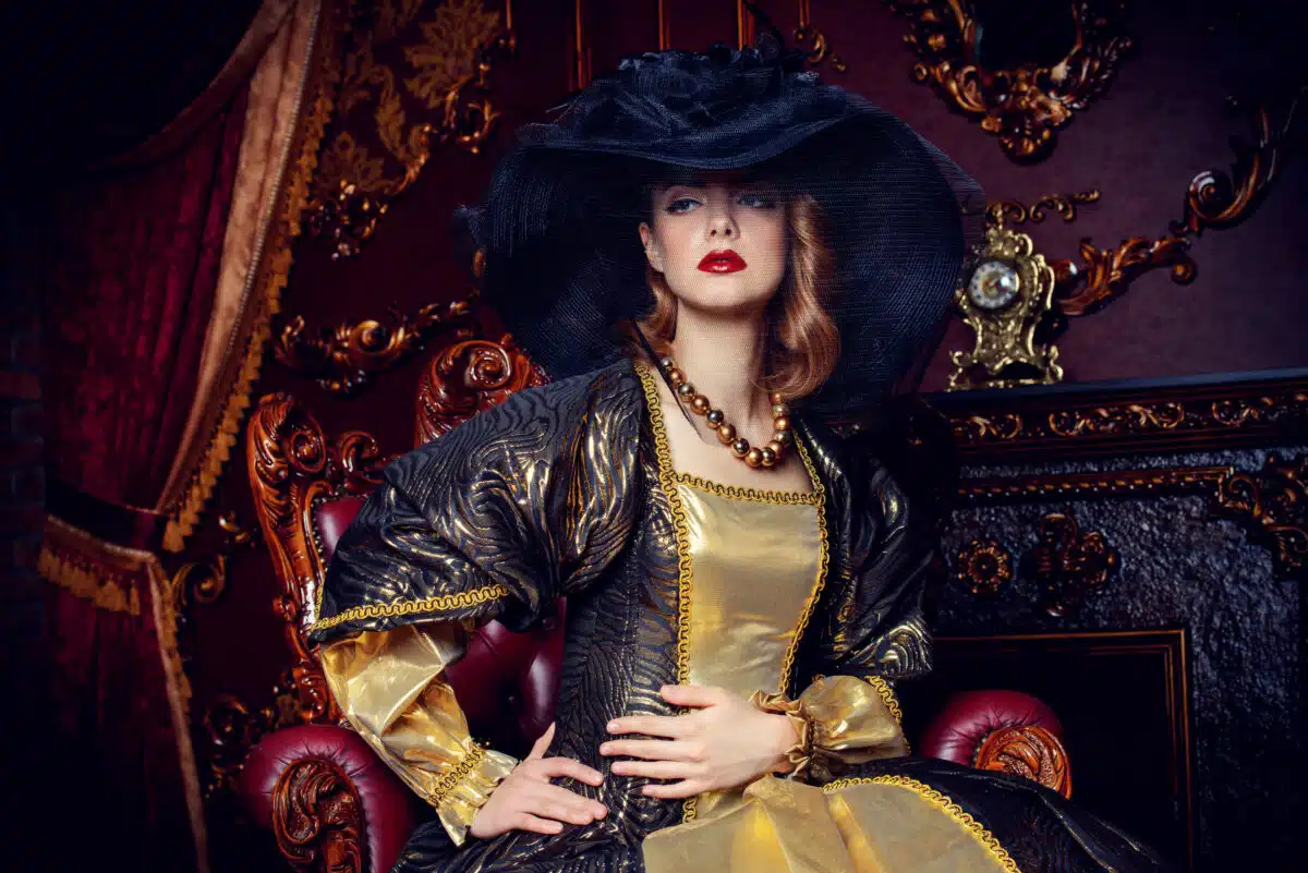 aristocratic lady in black hat sits on a luxury chair