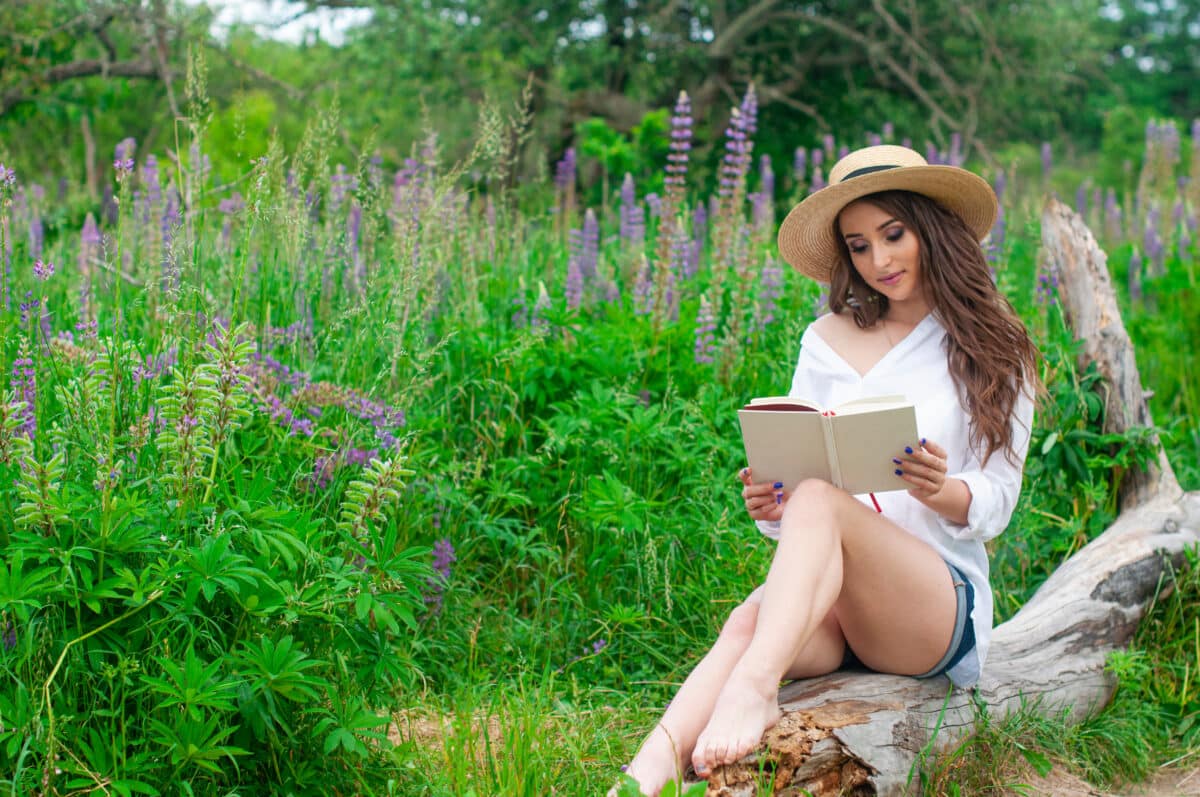 Pretty attractive girl reading book relax on nature field of flowers