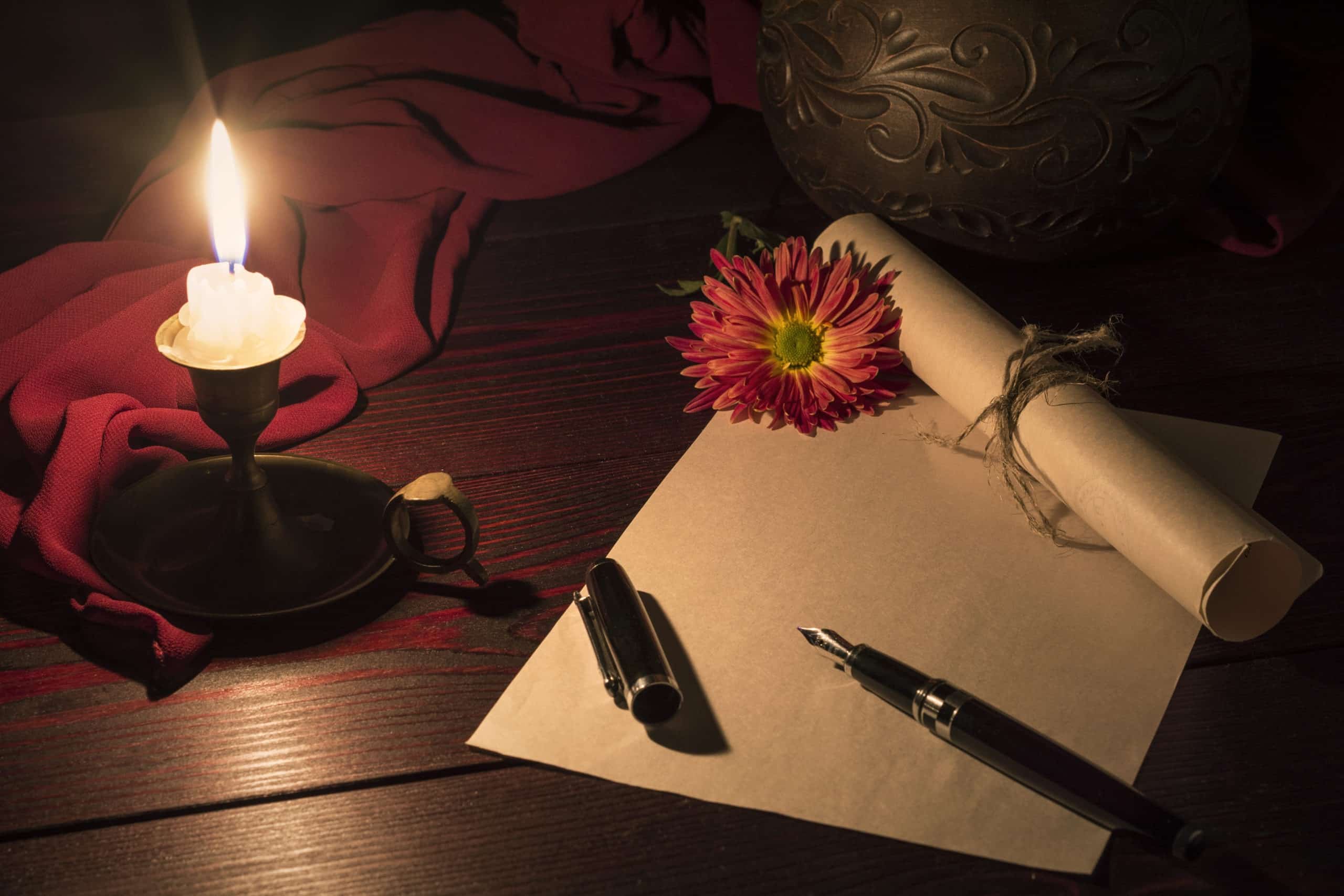 The candle illuminates the desk with pen and paper
