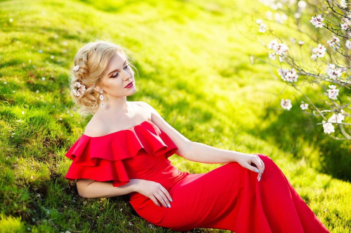 Fashion Art Beauty Portrait. Beautiful Girl in Fantasy Mystical and Magical Spring Garden. Model Woman wearing Long red dress