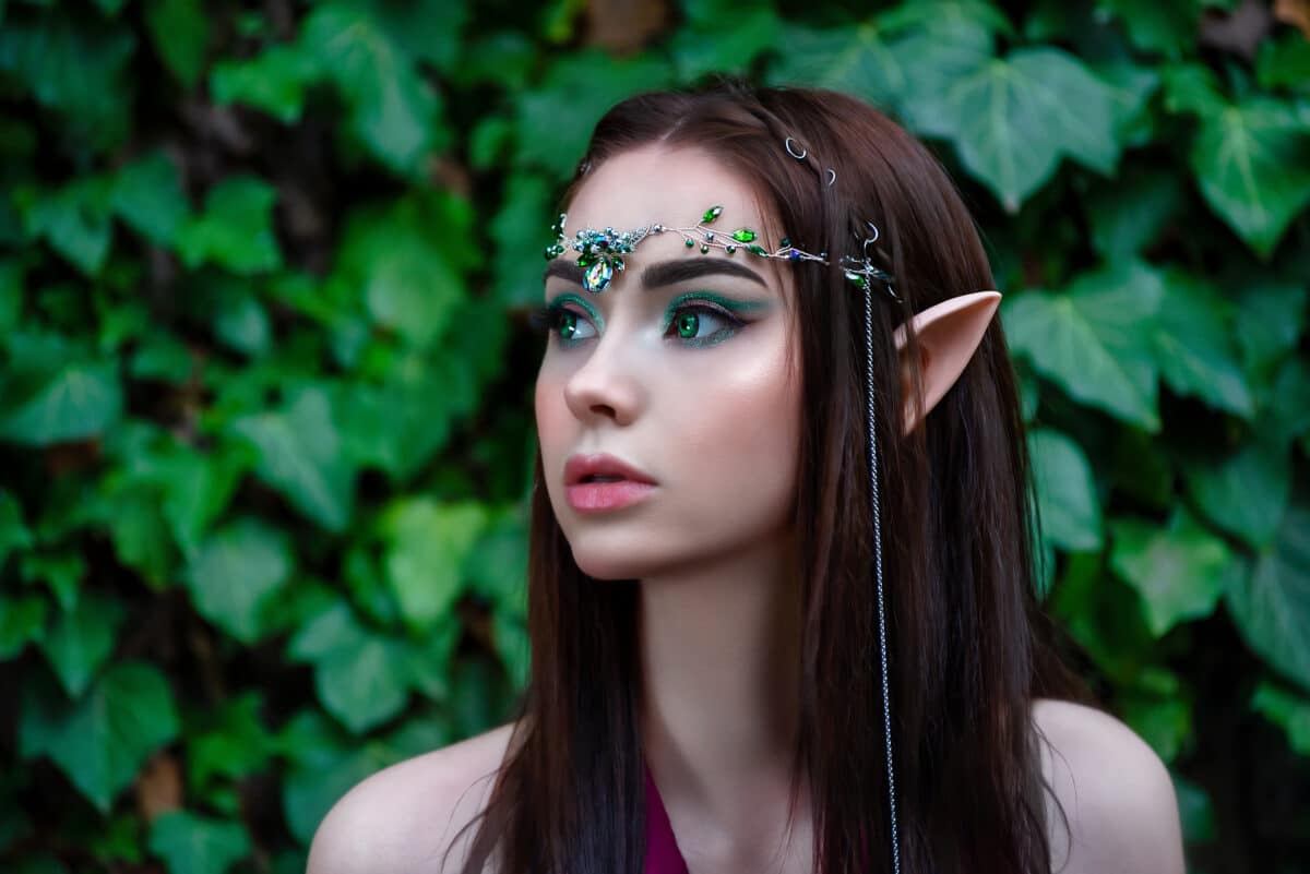 Portrait of a fantasy elven princess in a green forest. Summer nature forest green tree. Long hair, pointed elf ears, green eyes, jeweled diadem