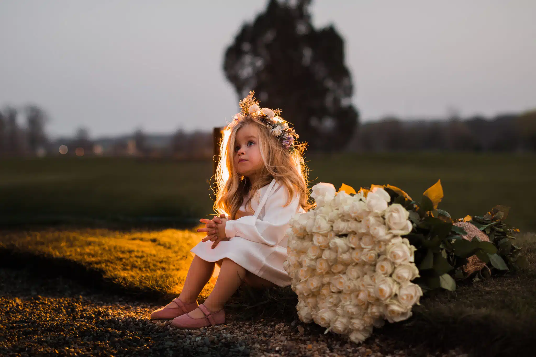 Beatiful little girl in a white dress  with a big bouquet of whi