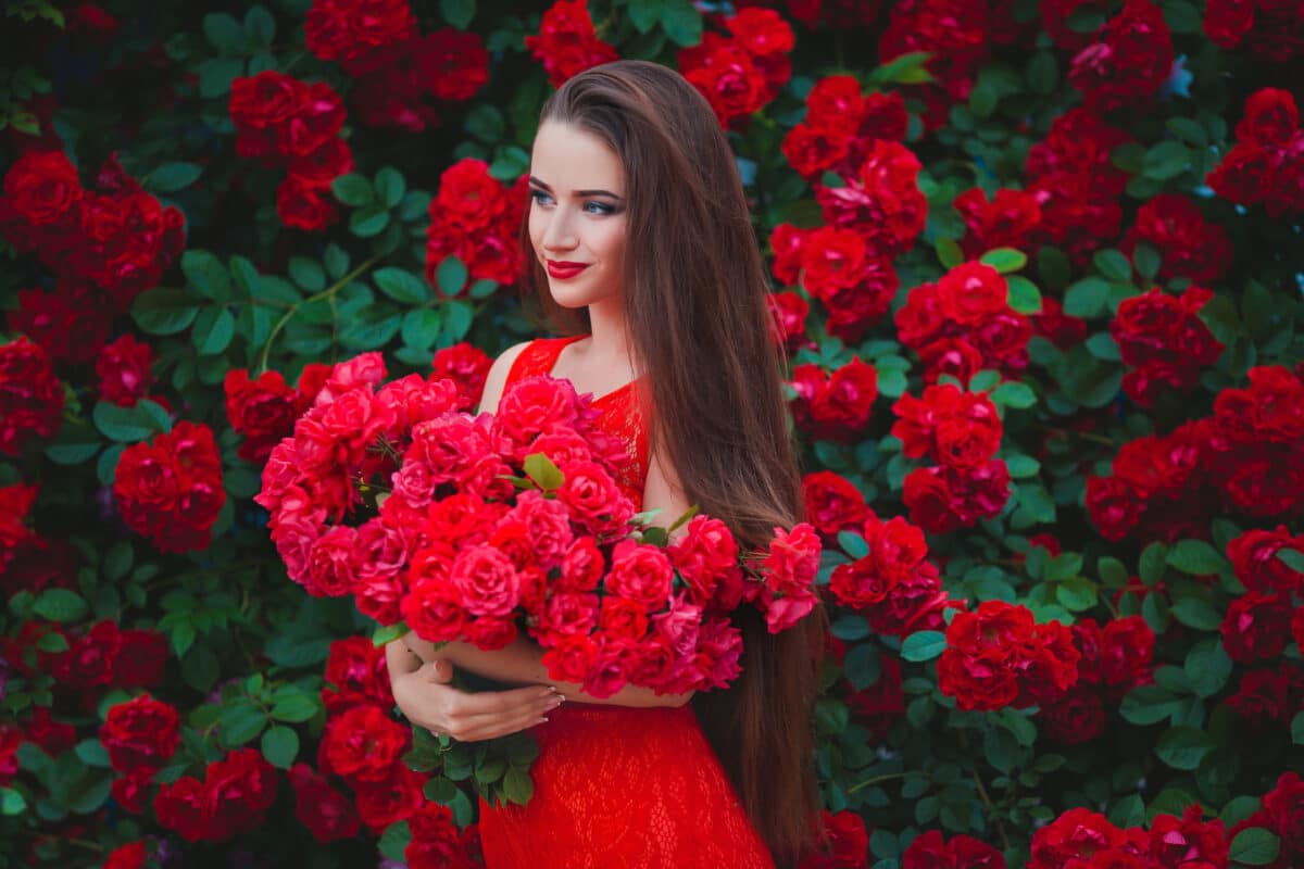 Beautiful portrait of sensual brunette young woman close to red roses