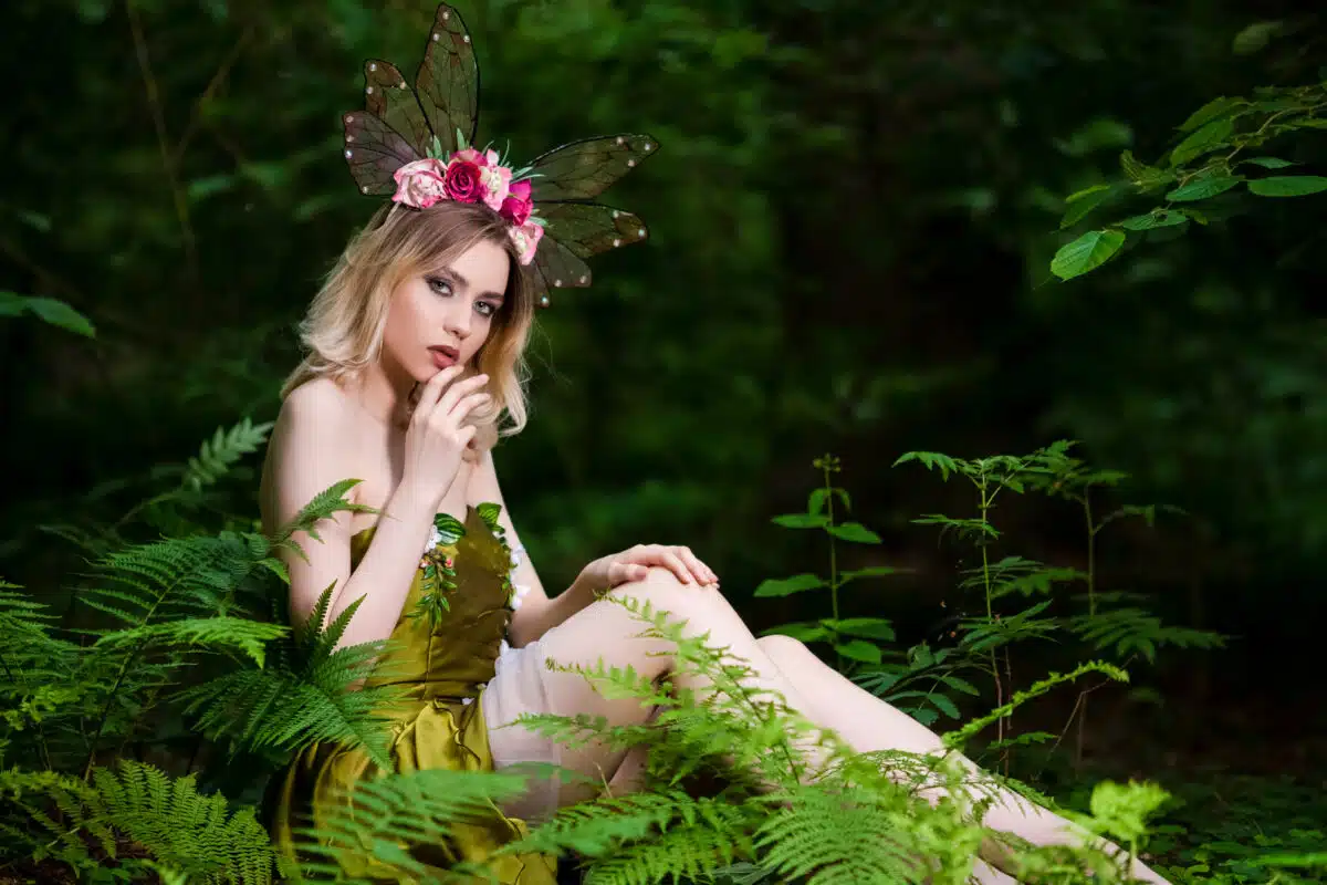 Portrait of Beautiful Sensual Caucasian Girl in Green Decorated Dress Posing in Forest Outdoor.