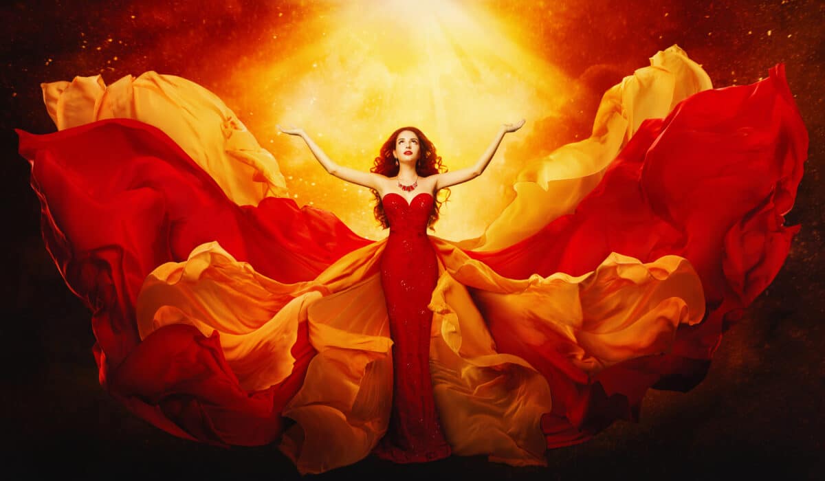 Woman dressed in fiery red flying towards the bright orange light above her