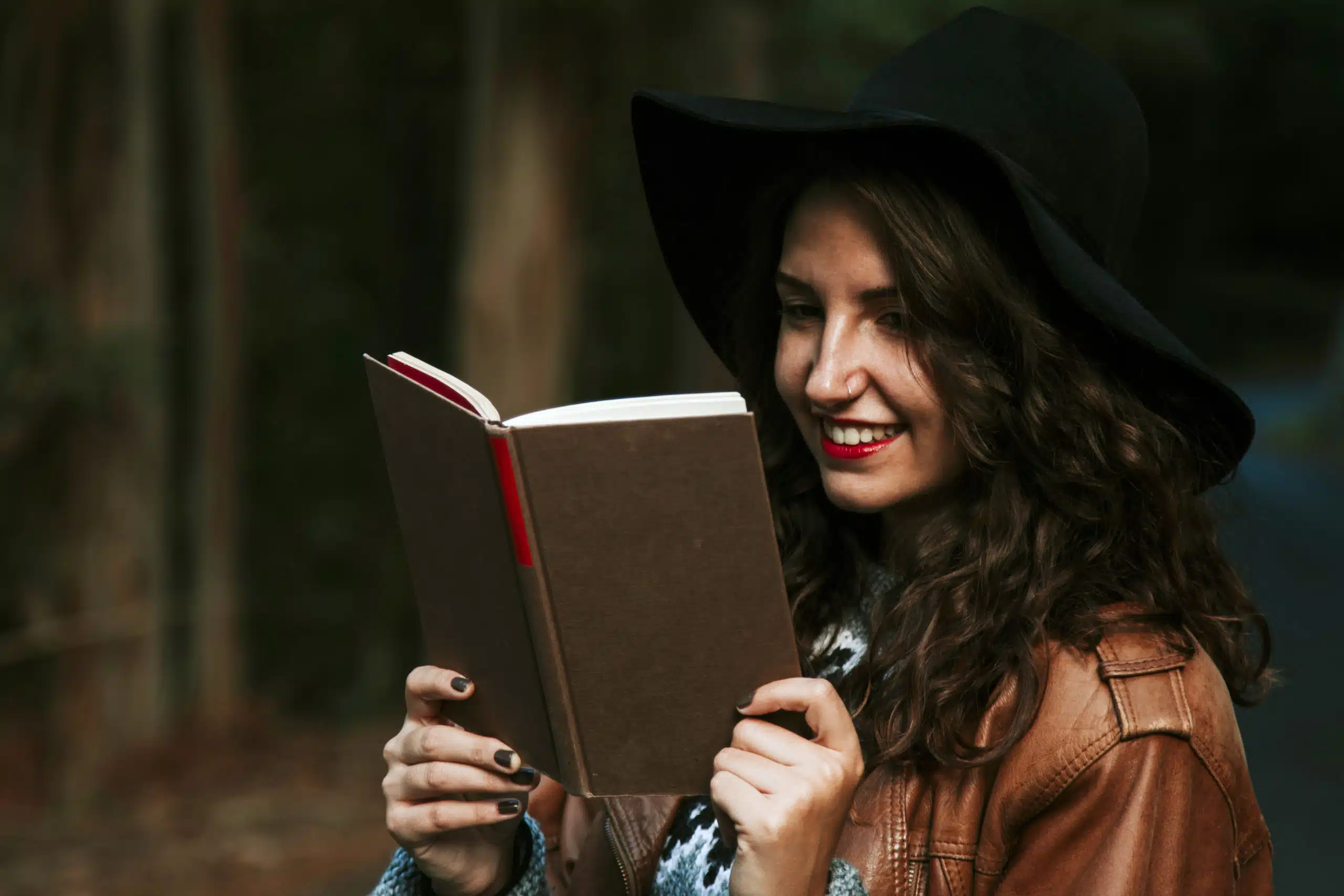 Amused young lady reading a book outdoors