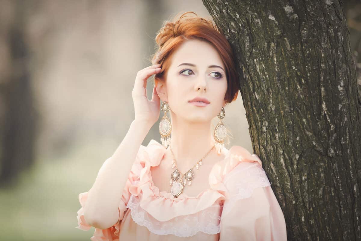 a young victorian red head leaning against the tree 