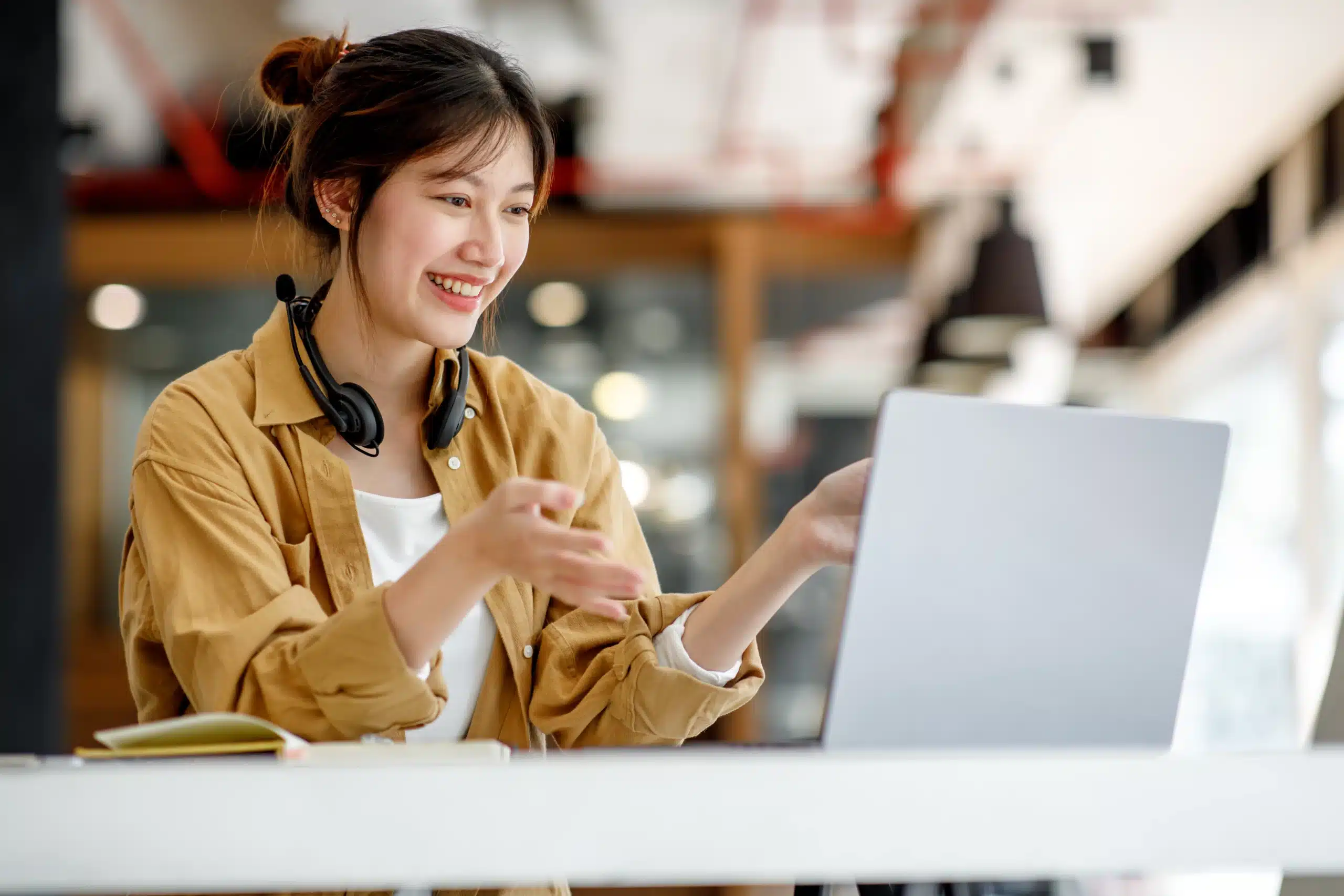 Young happy smiling woman wearing headphones working on laptop