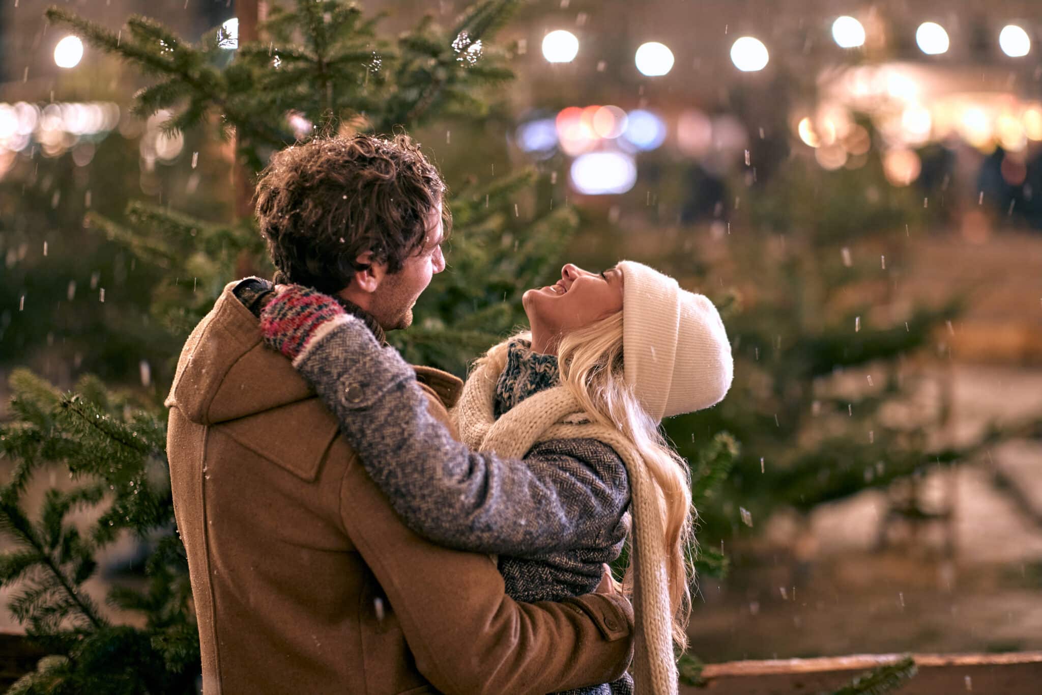 Man and woman hugging in front of a christmas tree
