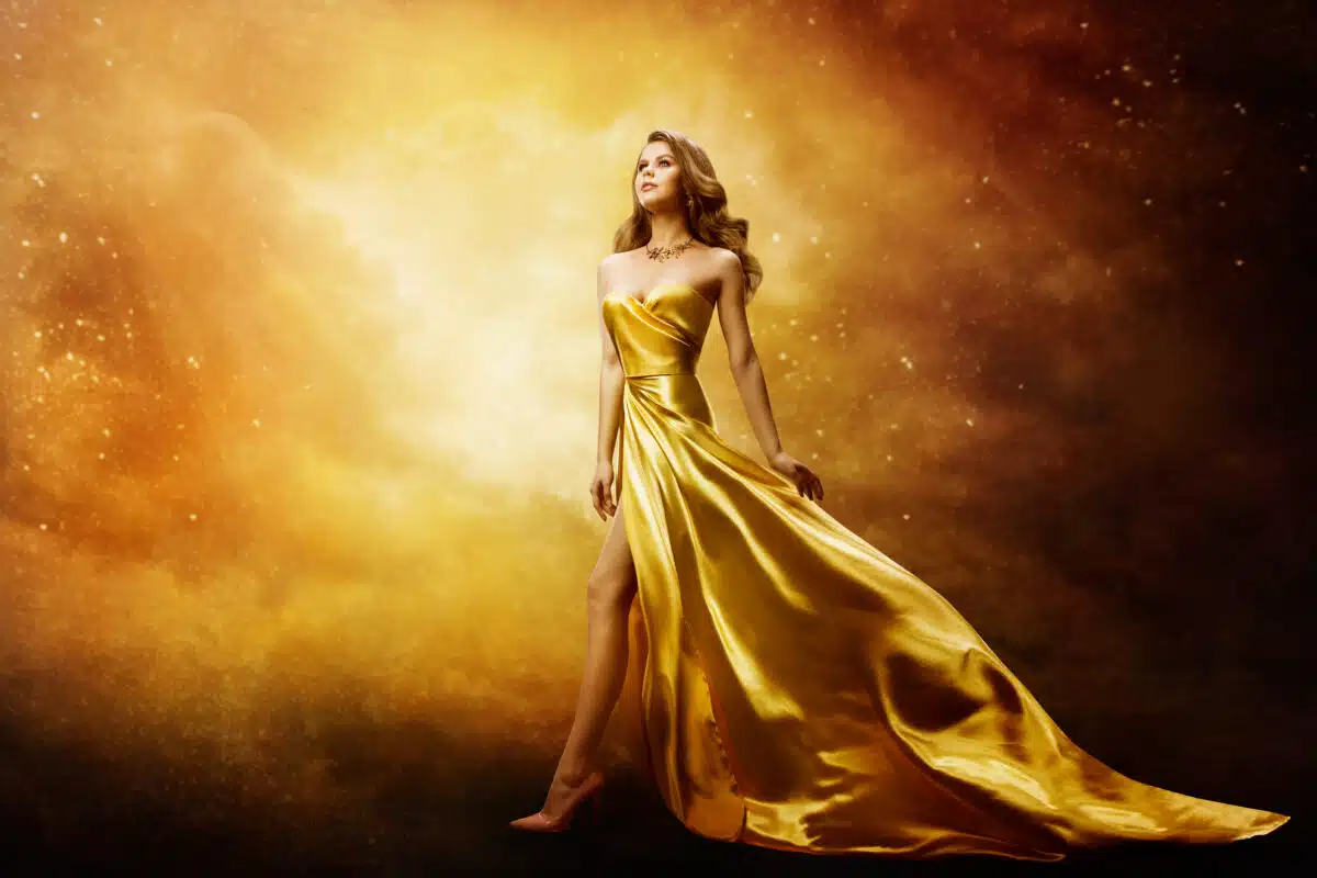 woman in gold dress looking up the bright golden space above