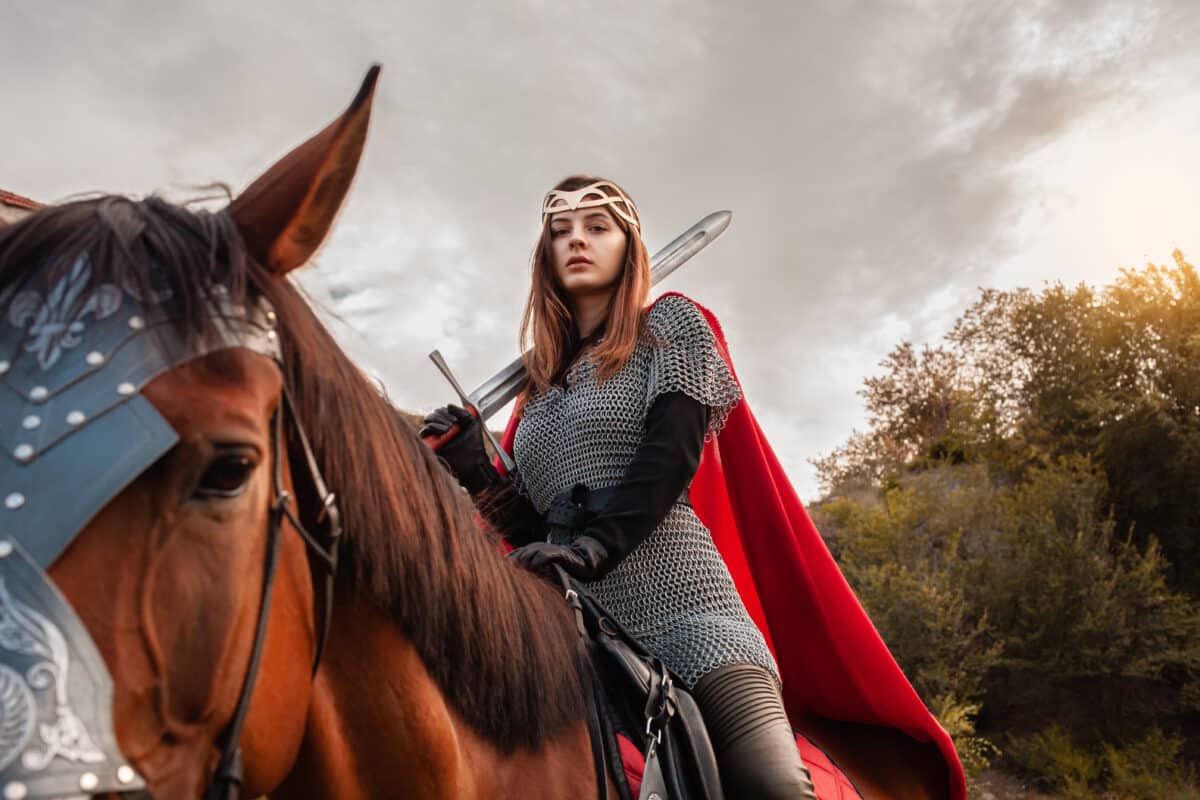 a beautiful female knight with a sword in a medieval suit riding a horse