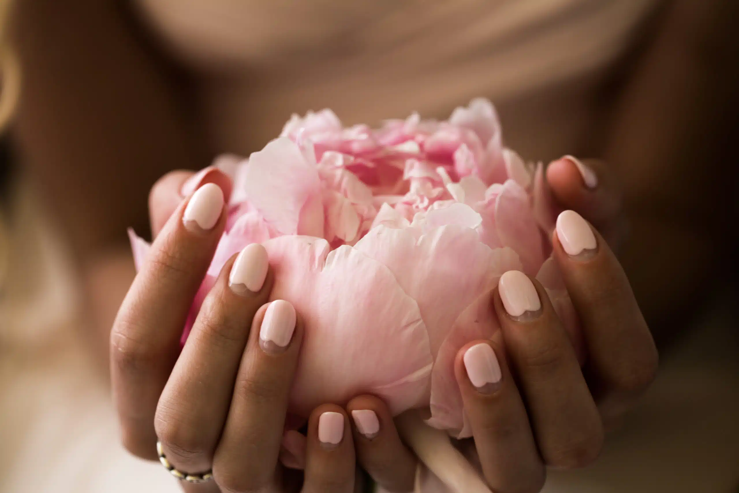 Girl with beautiful delicate hands holding peony flower