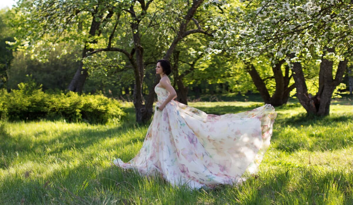 a beautiful fairy in a gown walking on grass in summer