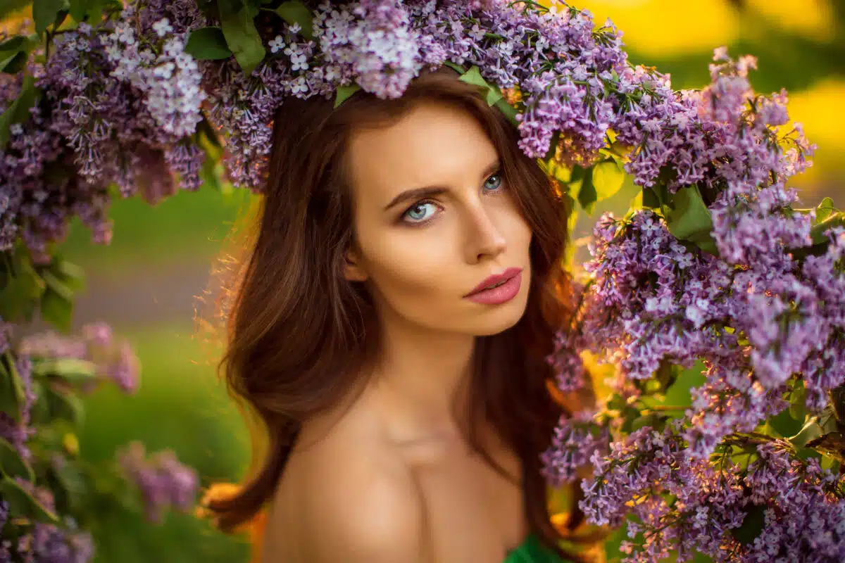 attractive woman in green dress posing near lilac flower