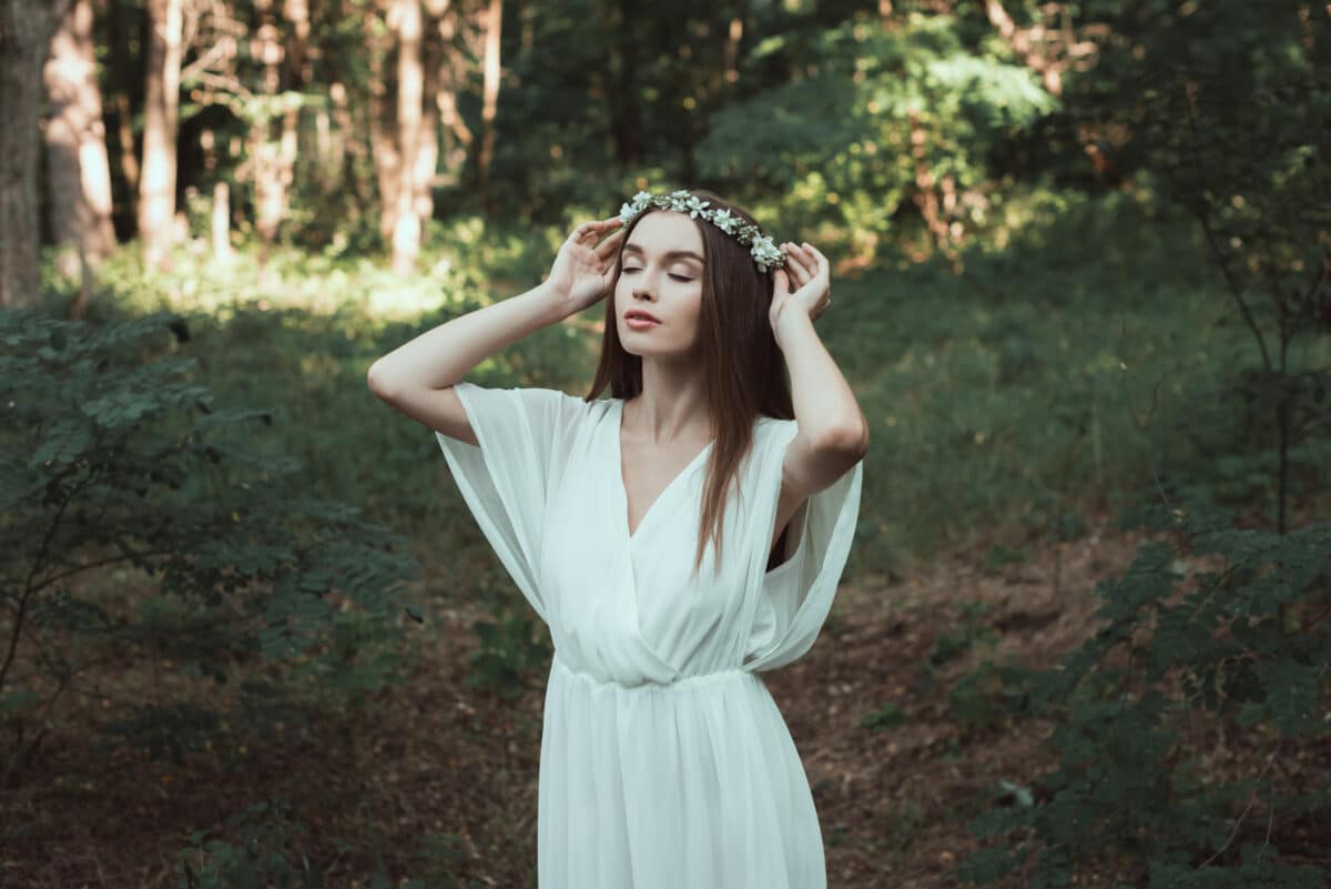 tender girl with closed eyes wearing a floral wreath in forest