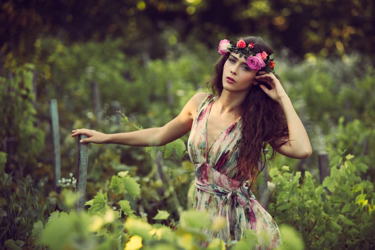 romantic maiden with a flower head wreath in the vineyard