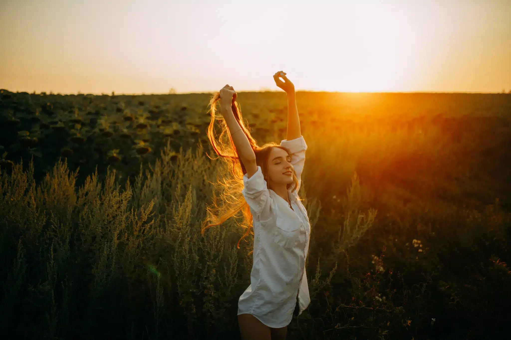 Happy joyful woman is walking on meadow at sunset.