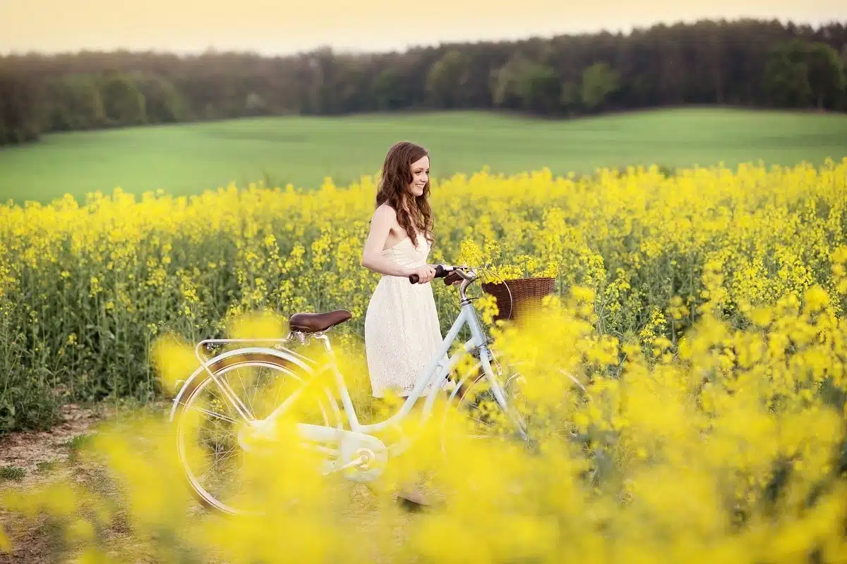 Young woman with bike strolling in a field of flowers.