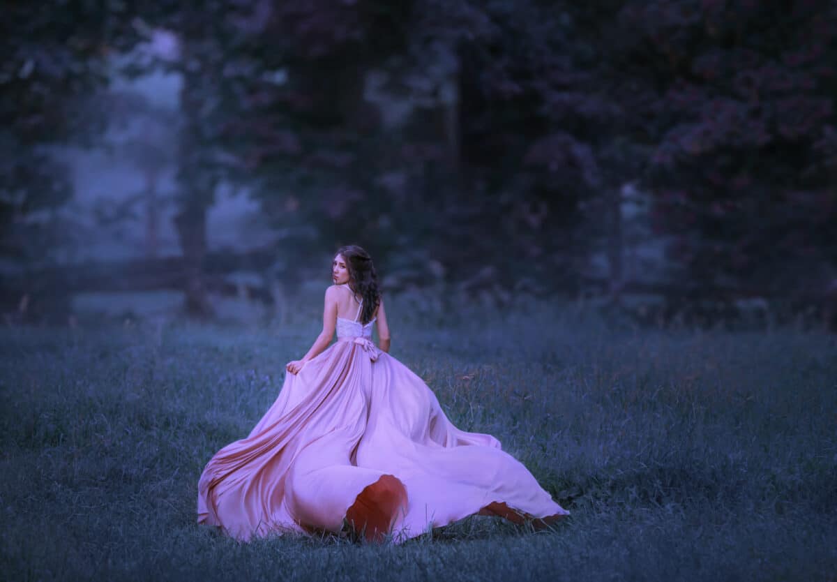 A brunette girl runs in a forest that has shrouded in mist. A lady in a pink flying, waving, long dress with a train. Scared face. Background in cold colors the twilight haze.