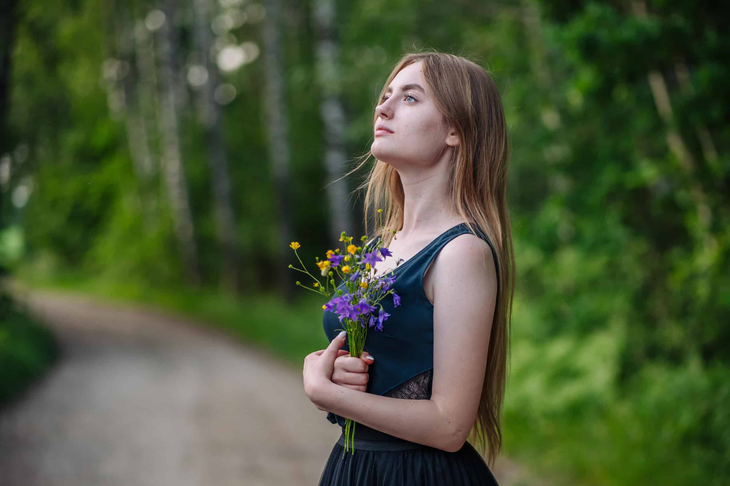 young woman with a bouquet of wild flowers on the road at a village