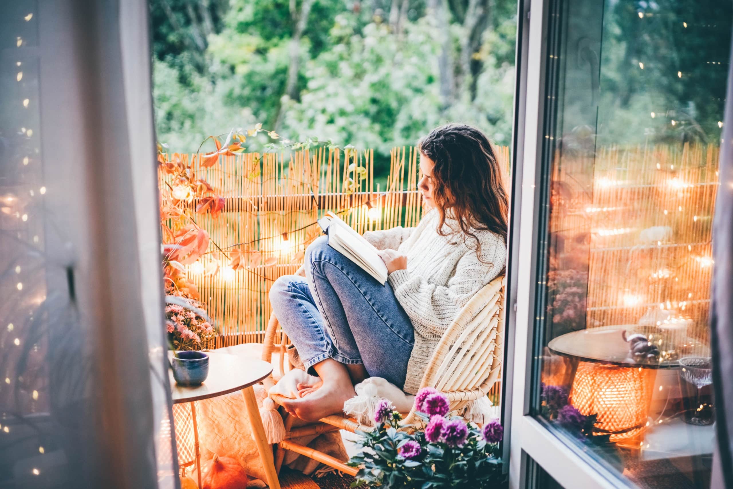 Woman relaxing on cozy balcony, reading a book.