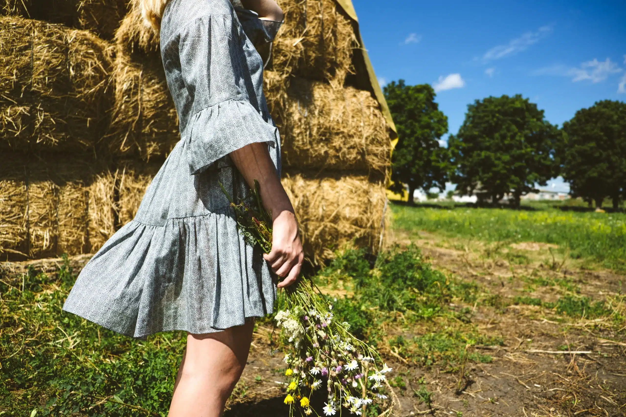 Young woman holding wild flowers, enjoying the farm life.