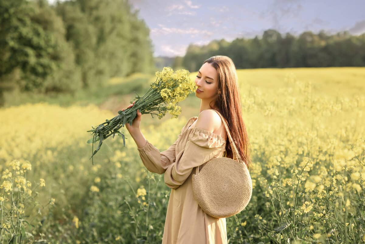 Young woman in the field of flowers with bouquet
