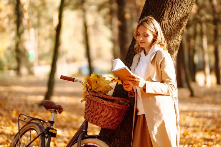 Stylish woman reading a book in the autumn park. 