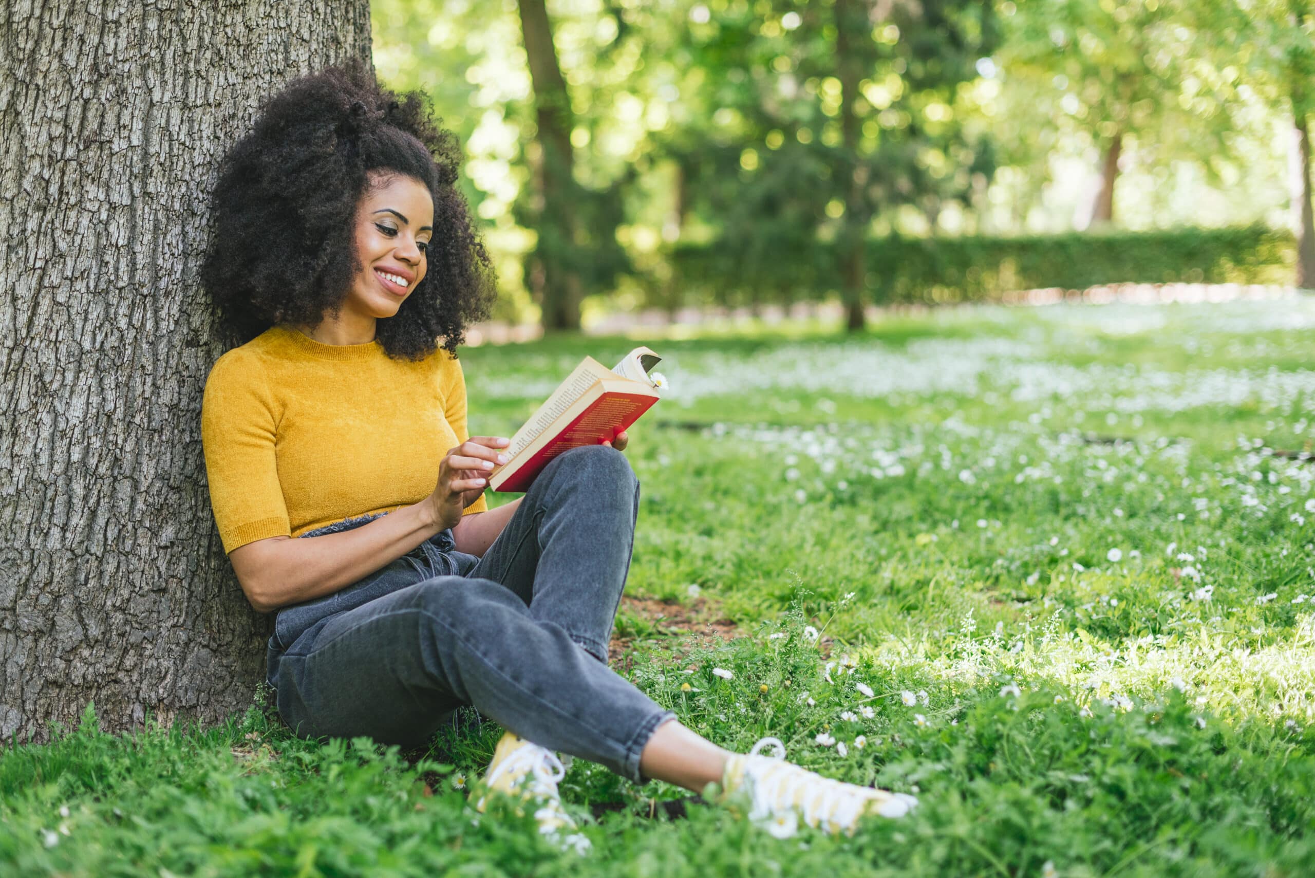 Pretty african american woman reading a book in a garden.