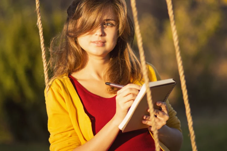 cute woman on a swing with a notebook and pen 