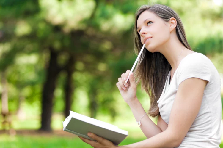 young woman at the park writes in her personal diary