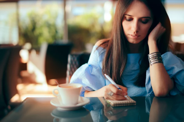 woman writing seriously while having coffee