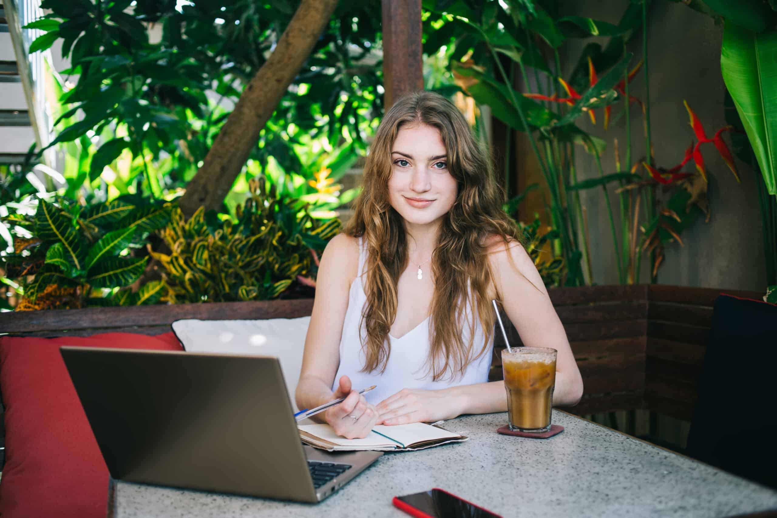 Young female writer sitting and working in tropical street cafe
