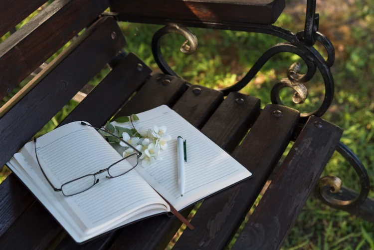 diary, reading glasses, jasmine flowers on the park bench