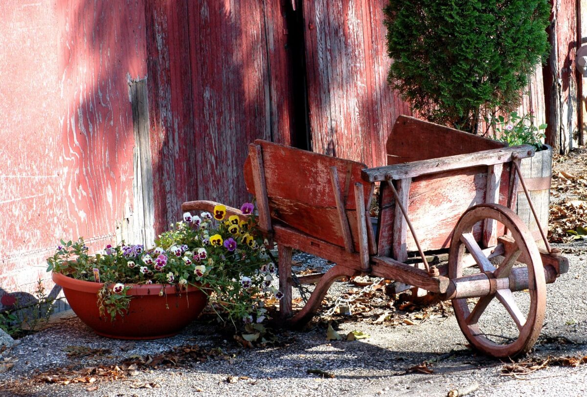 a red old wheelbarrow outside a wooden cabin