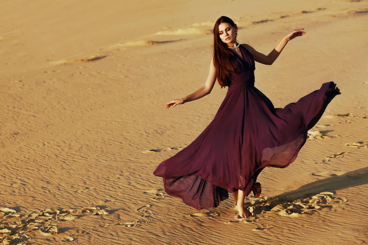 young beautiful woman dressed in maroon red as she walks in the desert