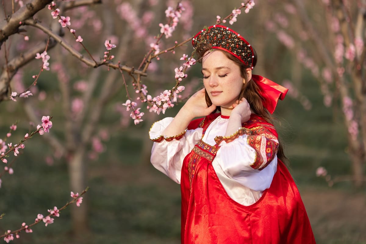 A lady dressed in traditional clothes with closed eyes enjoys the silence and beauty of spring